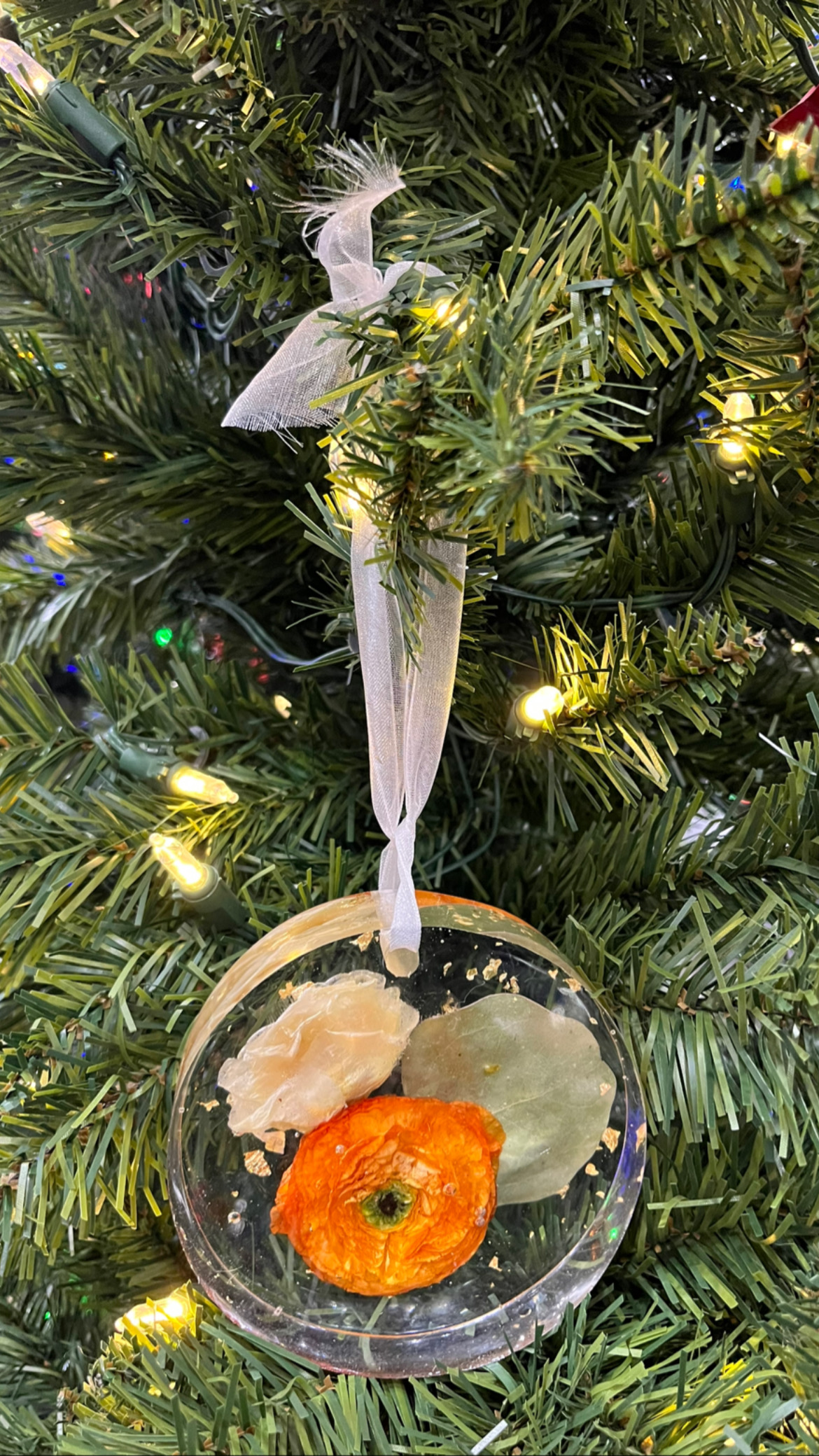 Resin Floral Preservation Ornament hanging with delicate preserved wedding bouquet petals inside.
