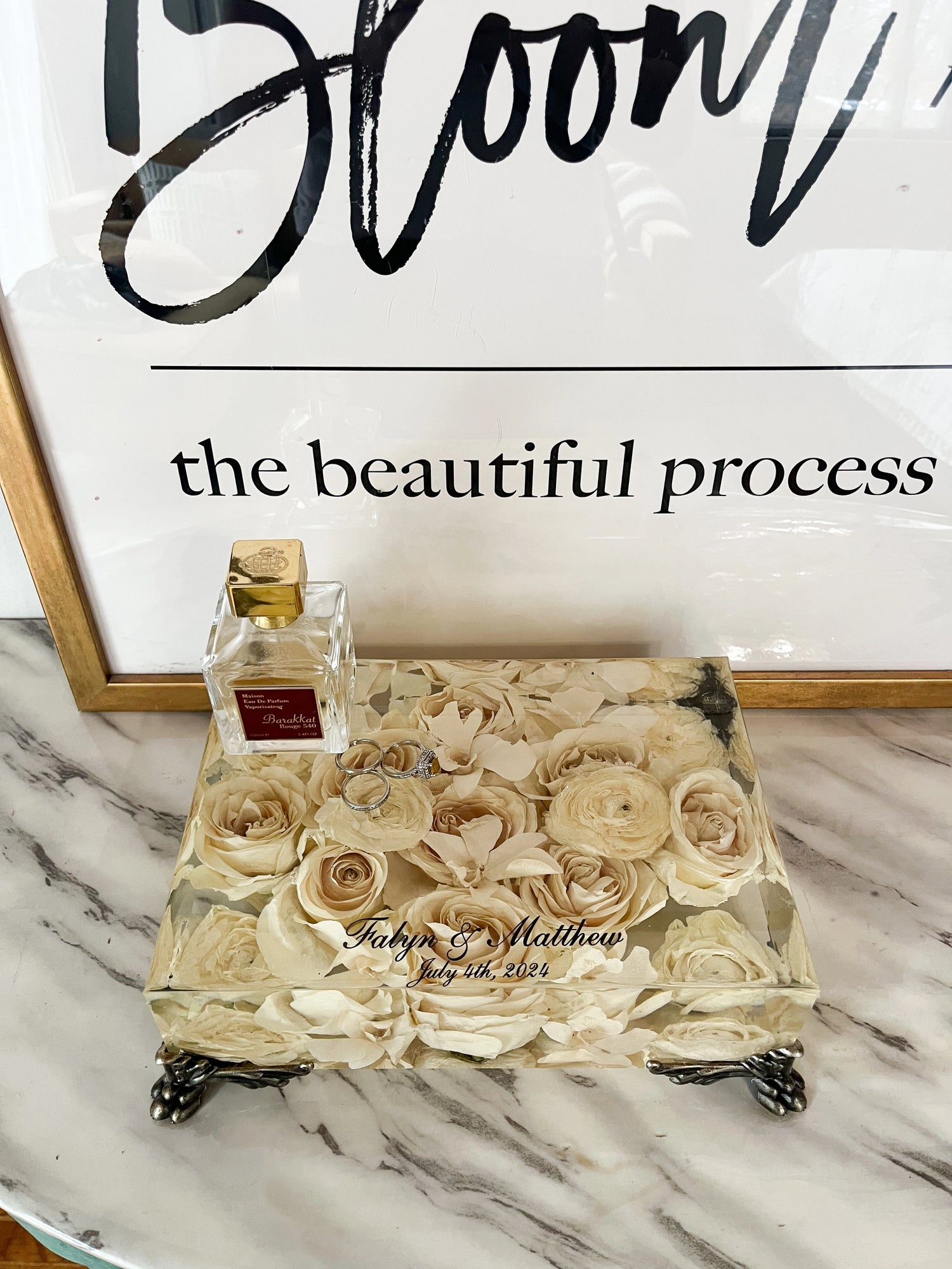 Decorative box with preserved roses and a bottle of perfume on a marble surface, with &