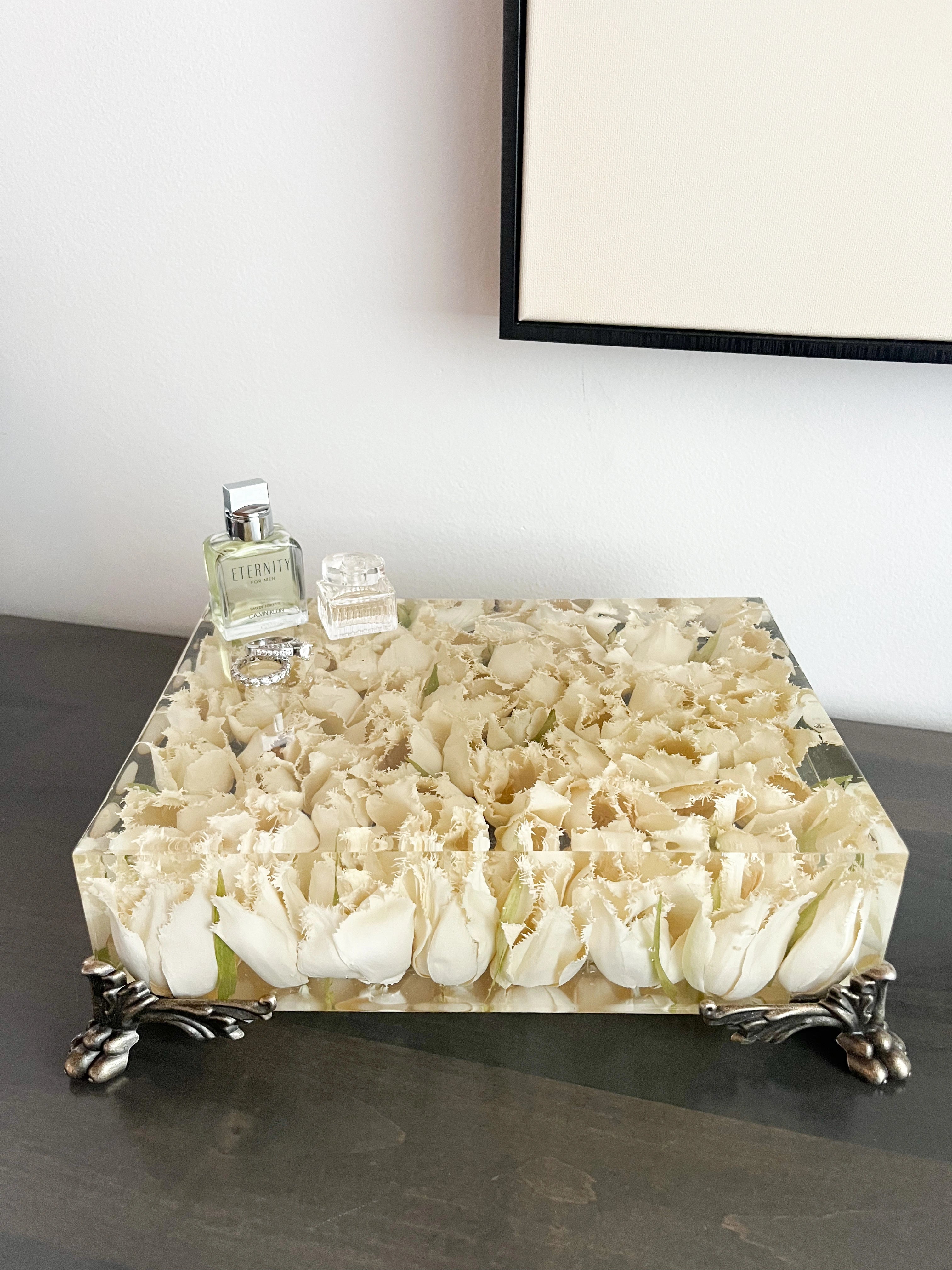 Decorative table with floral design and a bottle on top, against a plain wall.