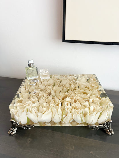 Decorative table with floral design and a bottle on top, against a plain wall.
