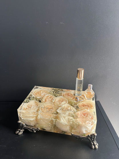 Decorative tray with floral design holding two bottles against a dark background