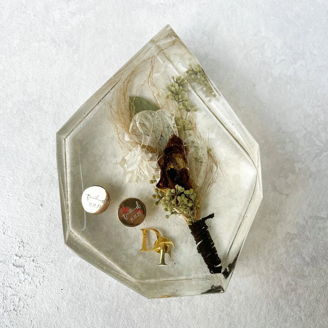 Hexagonal glass display case with preserved flowers and decorative items on a light background